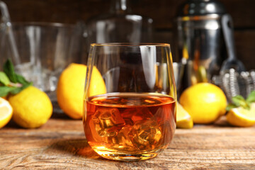 Glass of rum with ice cubes on wooden background