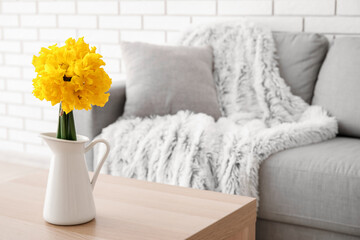 Fototapeta na wymiar Vase with narcissus flowers on table in living room