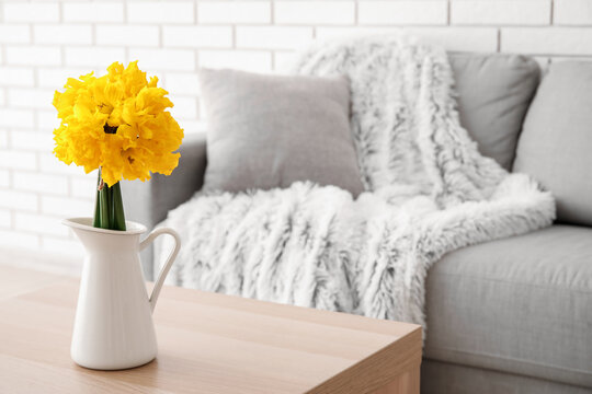 Vase with narcissus flowers on table in living room