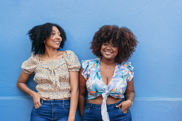 Two African-American women standing in front of a wall.