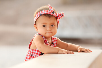 Lifestyle portrait of infant baby girl standing and holding on to a bench on 4th of July day