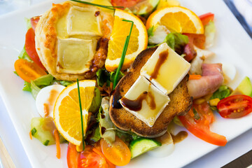 Salad with goat cheese, orrange, honey and vegetables at plate, dish of french cuisine