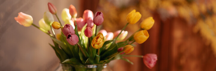 Fresh spring colorful bouquet of tulips in a vase against the backdrop of a warm, cozy room....