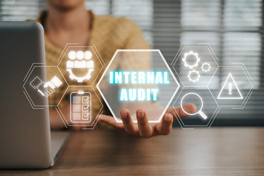 Internal audit concept, Person working on laptop computer and hand holding internal audit icon on virtual screen.