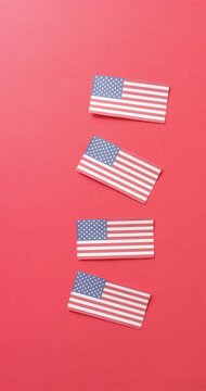 Vertical video of four national flags of usa lying on red background with copy space