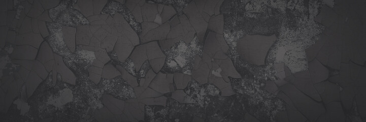 Dark wide panoramic background. Peeling paint on a concrete wall. Faded dark texture of old cracked flaking paint. Weathered rough painted surface with patterns of cracks. Shaded background for design