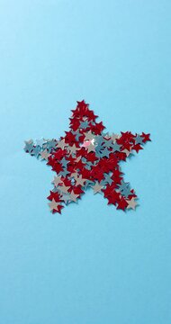 Vertical video of star shape of red and blue stars lying on blue background with copy space