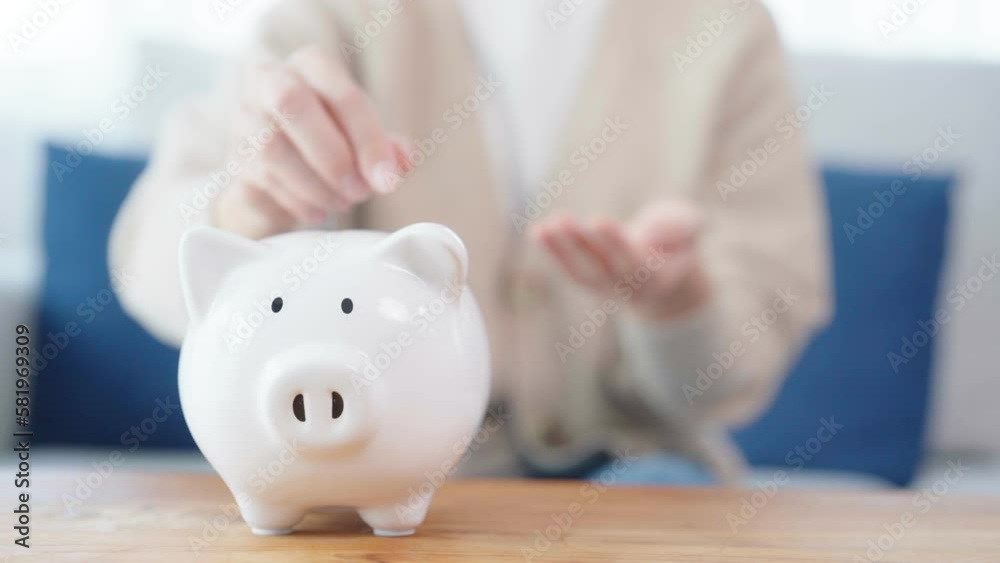 Wall mural asian woman putting coin in piggy bank. save money and investment concept