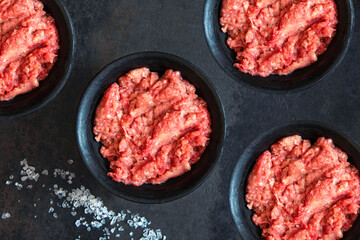 Homemade minced meat in a black bowl and salt on a black background. Fresh Raw mince. Top view