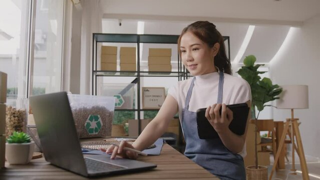 Cloud ERP martech for smart SME. Go green vendor net zero ESG store using easy CRM social media platform on tablet laptop at office. Young adult seller woman asia people happy work at retail box shop.