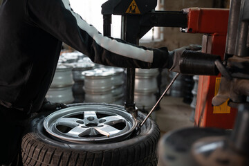 closeup of male hand changing tyre on wheel in workshop
