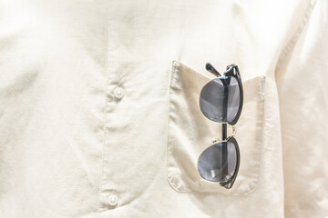 Obraz na płótnie Canvas sunglasses in shirt pocket. put sunglasses in pocket, going on vacation. shirt pocket with sun glasses.