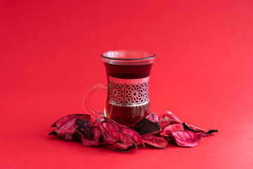 Turkish Tea in a cup with Flower petals around it, Red background National Tea day Selective focus