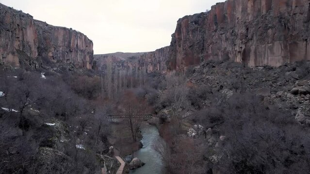 Low Aerial View Of Ihlara Valley In Cappadocia, Turkey. Drone flying between trees in winter.