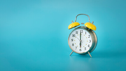 Retro silver alarm clock. 6:00, am, pm. Blue background.