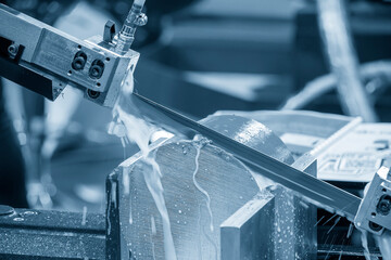 The operation of band saw cutting machine cutting the metal shaft parts with coolant method.