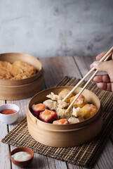 dim sum dumplings in bamboo steamer with sauce on wood table - obrazy, fototapety, plakaty