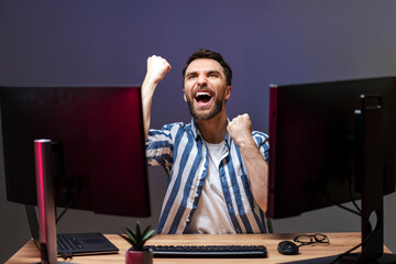 Overjoyed man gamer playing computer game at home, winning, celebration concept 