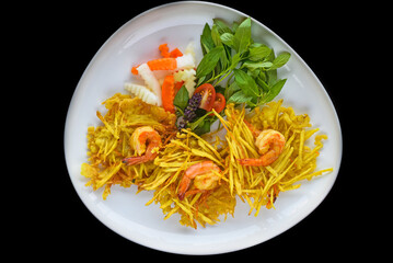 vietnamese dish with fried shrimps on fried grated potatoes isolated on black background top view