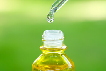 Dropping serum collagen moisturizer of face into clear yellow bottle soft light background. Protector skin Treatment facial essence oil, Vitamin C. Beauty and spa Concept.