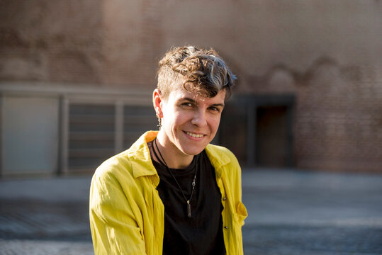 Portrait of a non binary person looking at camera while posing outdoors.