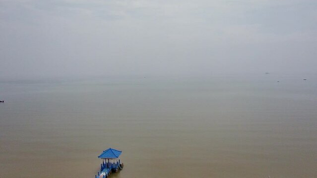 Aerial view of the white sand beach with a blue pier and fishing boats leaning against the shore