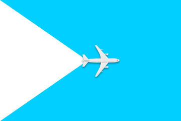 Naklejka premium Flat lay of miniature toy airplane on white and yellow background. Travel items on a blue background.