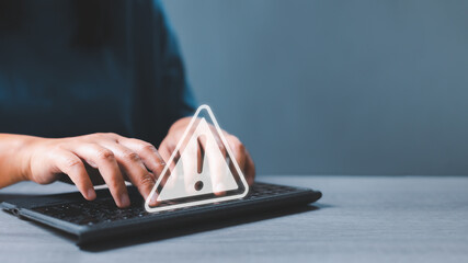 Businesswoman hands on computer keyboard got warning sign icon with virtual screen. Warning or...