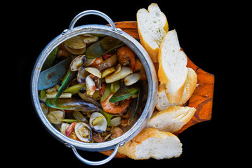Sautéed seafood in pot close up isolated on black background top view