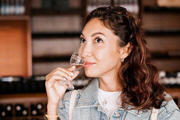 A beautiful woman takes a moment to savor the taste of a white wine sample in a winery, her glowing in delight.