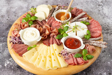 Fototapeta na wymiar Wooden plate with delicacies. Brie cheese, blue cheese, salami, prosciutto on a wooden board.