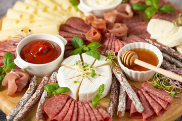 Wooden plate with delicacies. Brie cheese, blue cheese, salami, prosciutto on a wooden board.
