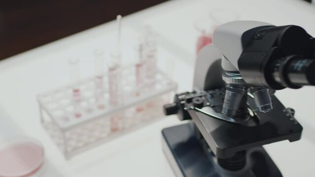 Above voew of microscope, group of flasks with liquid substance, petri dish and beaker on workplace of modern scientist or biochemist in chemical laboratory