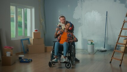 Fototapeta na wymiar A white man wheeling an African American woman in a wheelchair into the room. A young couple in big headphones enjoys music, sings using a roller as a microphone.