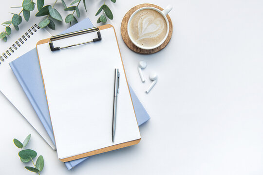 Modern white office desk table with coffee, notebook and other supplies.