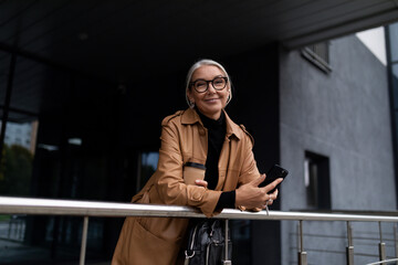 Fototapeta premium caucasian mature adult female accountant with gray hair standing on the steps of a business center