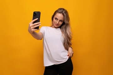 girl takes a selfie on the phone on a yellow background