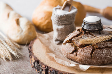 Fresh delicious bread close-up and salt. Freshly baked sourdough bread with a golden crust on a wooden board. The context of a bakery with delicious bread. Confectionery products.