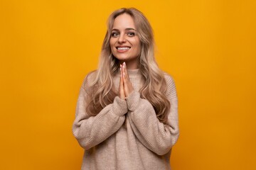 the girl folded her hands and asks for help on a yellow background