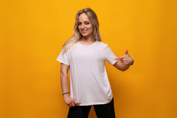 young woman showing on blank mockup white t-shirt on orange background