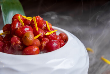 ice chilled red cherry tomato with sour plum salad in smoke white bowl on wood table asian banquet halal healthy appetiser menu
