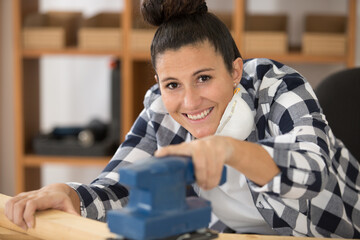female carpenter using electric sander