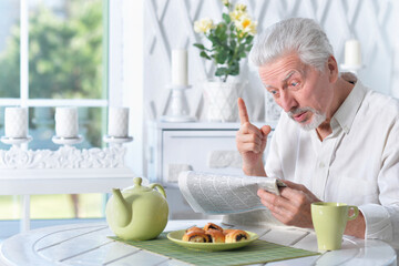 Emotional senior man reading newspaper