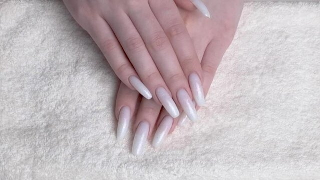 Beautiful professionally manicured female hands with painted in white color fingernails.