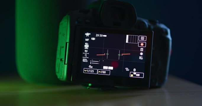 Reflex camera with screen on recording. Green lights to the left. Shooting equipment.