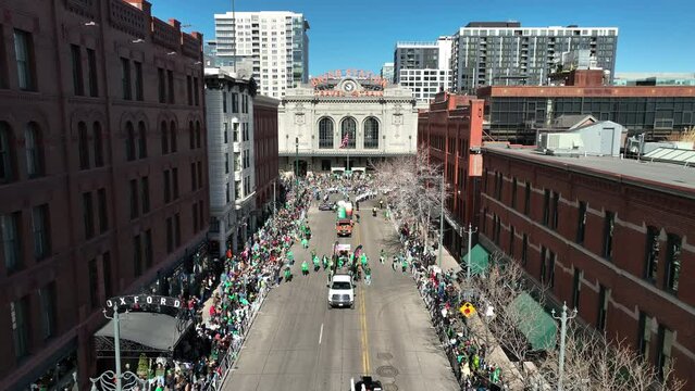 Lowering drone shot above a St. Patricks Day parade in downtown Denver.