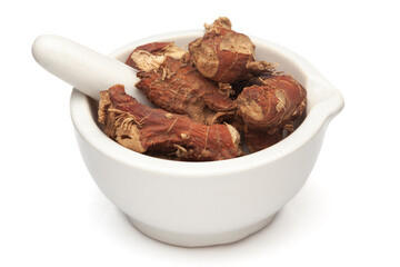 Closeup of Dry Kulanjan (Alpinia galanga) roots, in white ceramic mortar and pestle, isolated on white background.