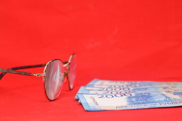 Pair of glasses and money on a red background. Selective focus.. Old banknotes of the former Soviet Union. USSR - rubles.