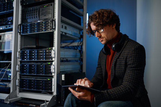 Young hipster man using digital tablet working in server room