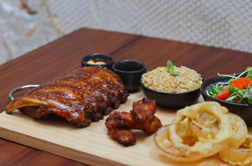 Grilled pork bbq ribs served with cherry tomatoes. basil and barbeque sauce on wooden cutting board over dark background. Close up